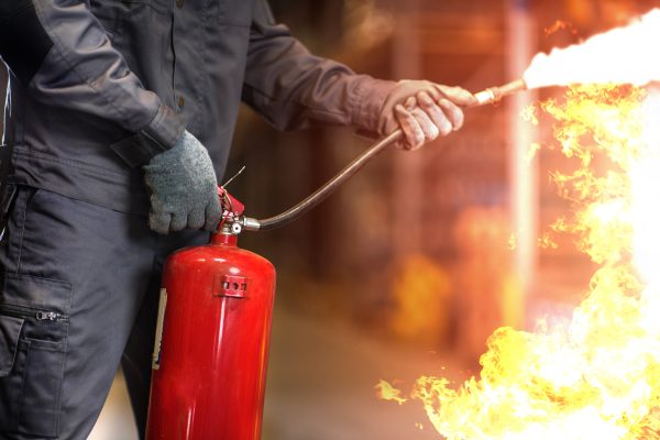 Man using fire extinguisher fighting fire closeup photo.